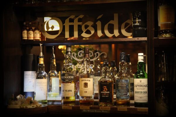 Schriftzug "Offside" mit Whisky-Flaschen