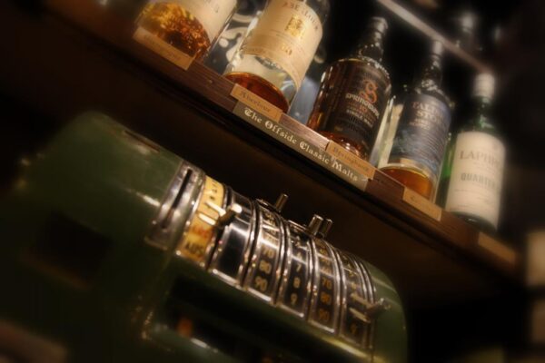 Close-Up von diversen Whisky-Flaschen und eine alte Registrierkasse